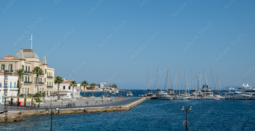 Naklejka premium Spetses island, Greece. Old neoclassical buildings, Yachts and sailing boats anchored at marina, blue sky