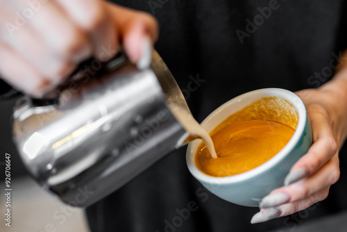 Close-up of hands pouring steamed milk into cup of espresso, creating intricate latte art. image captures the skill and precision of barista, highlighting the artistry involved in coffee preparation. 