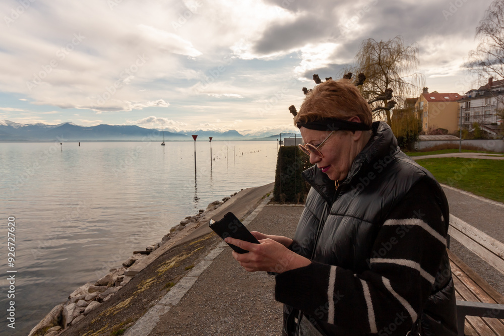 A mature woman on the embankment looks at her smartphone A mature woman on the embankment looks at her smartphone