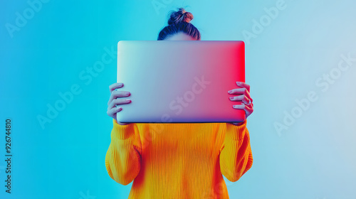 Person Holding Laptop in Front of Face with Colorful Gradient Background. photo