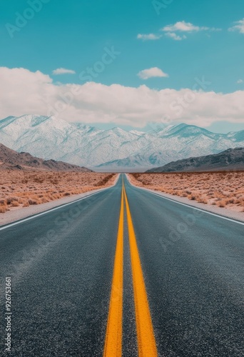 Open highway stretches toward snow-capped mountains under a clear blue sky