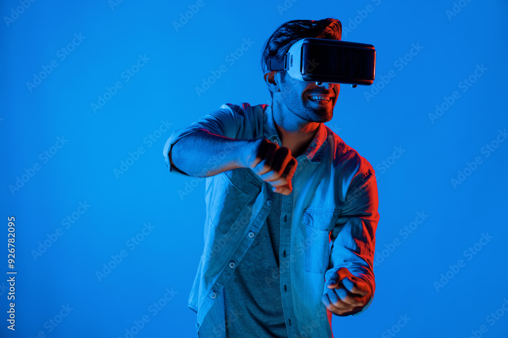 Smart man wear virtual goggle while move driving car hand gesture. Caucasian teenager using futuristic digital technology to enter virtual world while standing at colorful neon background. Deviation. Smart man wear virtual goggle while move driving car hand gesture. Caucasian teenager using futuristic digital technology to enter virtual world while standing at colorful neon background. Deviation.