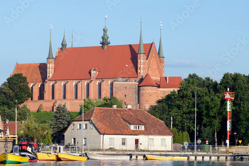 Red brick and roof Gothic cathedral set above a small seaport in warm sunlight set  photo