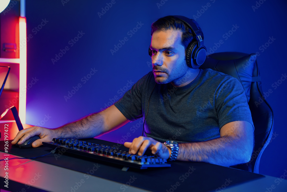Smart gaming streamer concentrating gaming players trying to pass the level at mission completed, using headset and mic for communicate others on streaming live at neon lighting studio room. Surmise. Smart gaming streamer concentrating gaming players trying to pass the level at mission completed, using headset and mic for communicate others on streaming live at neon lighting studio room. Surmise.