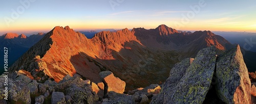 Panoramic view of Tatra Mountains at sunrise, capturing golden hour light on summer peaks and autumn foliage, with red hues on rocky landscapes, offering a breathtaking and detailed natural scene.