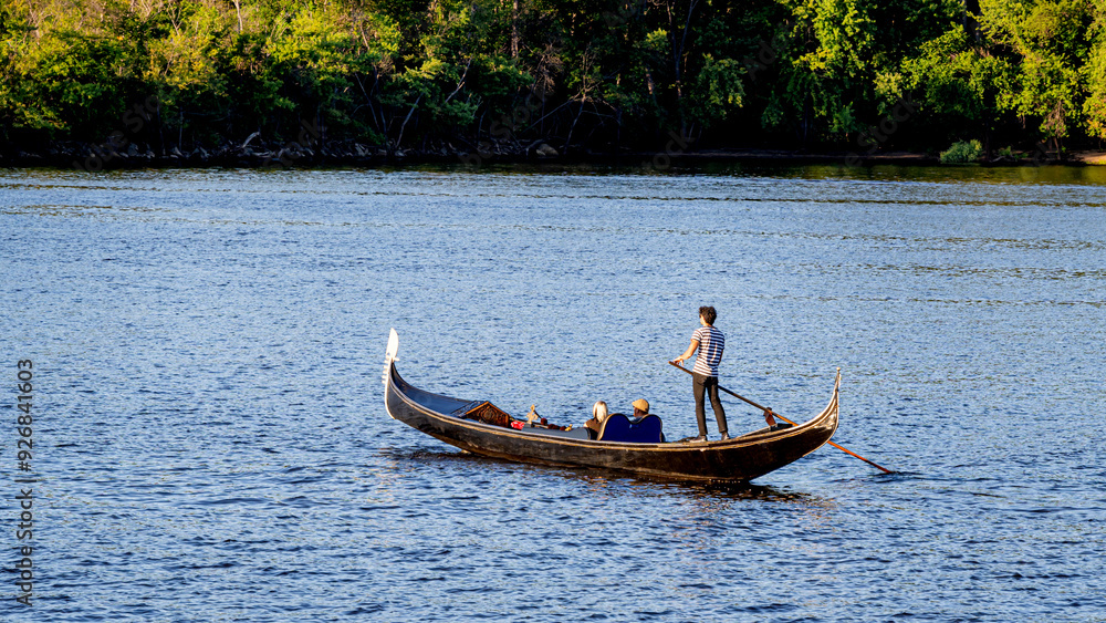 A gondolier punting gondola through st. croix river Minnesota A gondolier punting gondola through st. croix river Minnesota