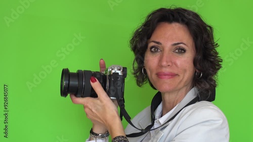 Cute, mid age business or teacher woman with blazer shooting photo and looking at camera. Chroma key green background with copy space.