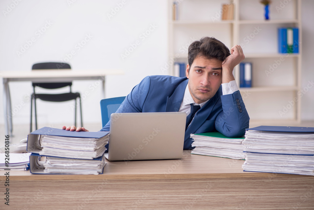 Young male employee and too much work in the office Young male employee and too much work in the office