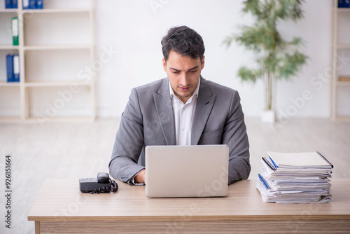 Young male employee and too much work in the office