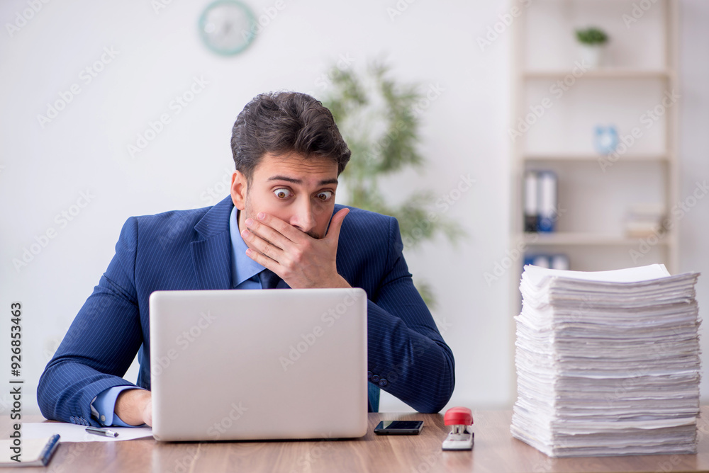 Young male employee and too much work in the office Young male employee and too much work in the office