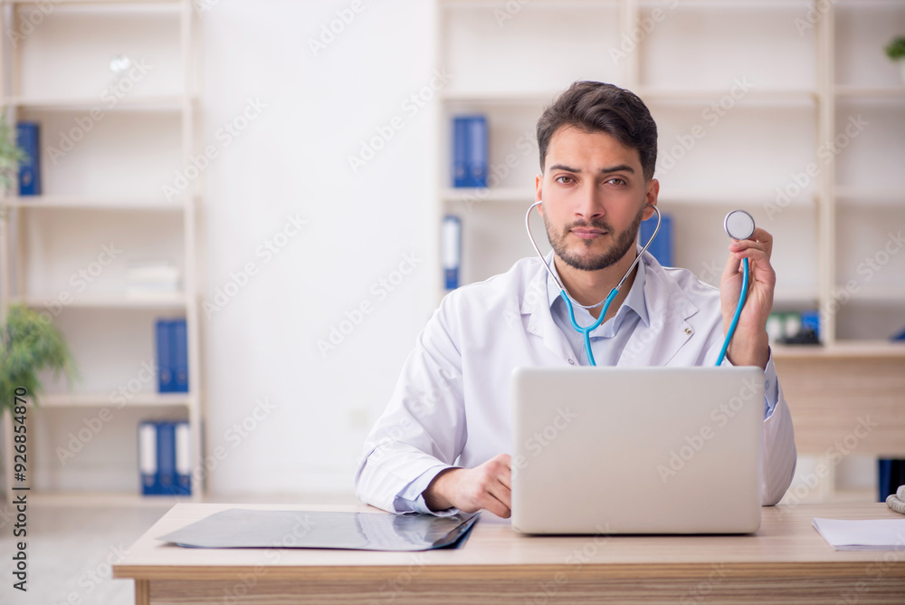 Young male doctor holding stethoscope at the hospital Young male doctor holding stethoscope at the hospital