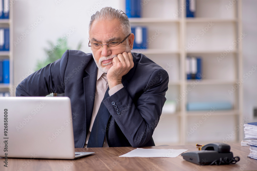 Fototapeta premium Old male employee working in the office