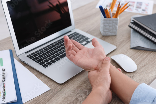 Canvas-taulu Man suffering from pain in wrist while working on laptop at table indoors, closeup