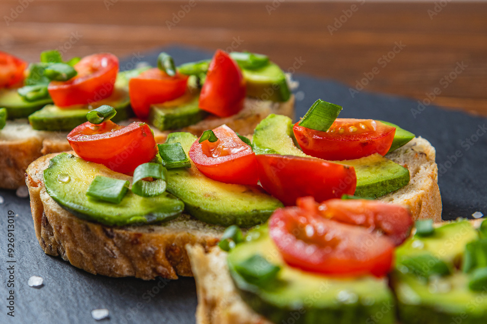 Avocado toast topped with tomato and green onion on a slice of carrot bread Avocado toast topped with tomato and green onion on a slice of carrot bread