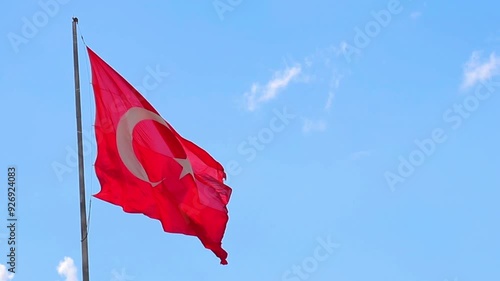 Slow motion Turkish flag waves against a clear blue sky, providing ample space for overlay text. photo