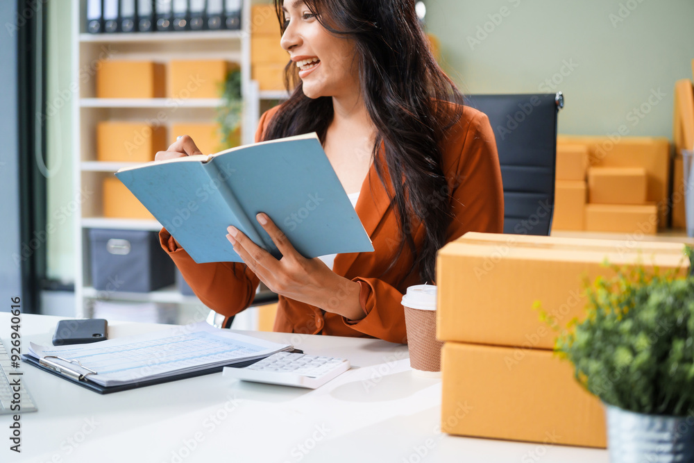 A young Asian businesswoman sits at her table, watching the computer screen.She analyzes, plans, and sells products online from home, smiling as she replies to comments and takes orders successfully. A young Asian businesswoman sits at her table, watching the computer screen.She analyzes, plans, and sells products online from home, smiling as she replies to comments and takes orders successfully.