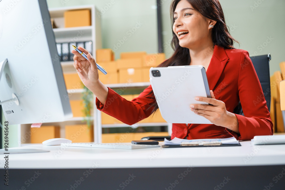 A beautiful businesswoman sits at the table, looking at the computer screen and talking on the phone. She analyzes marketing plans with a smile, feeling happy and successful in her online business. A beautiful businesswoman sits at the table, looking at the computer screen and talking on the phone. She analyzes marketing plans with a smile, feeling happy and successful in her online business.