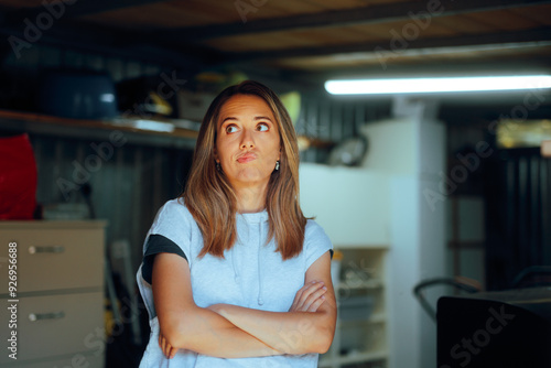 Free Download Funny Woman Feeling Puzzled Standing in a Storage Room. Frustrated millennial girl thinking how to declutter a warehouse space 
 - GFXLoad