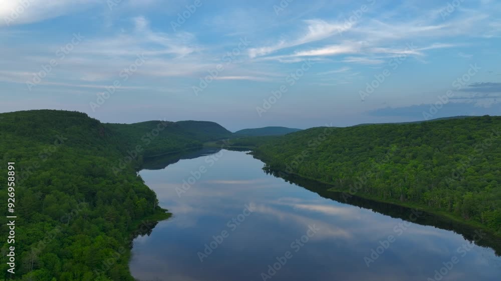 A breathtaking view of Lake of the Clouds at sunset during July, captured by drone footage in the Porcupine Mountains, Upper Peninsula, Michigan. The tranquil lake reflects the serene sky. A breathtaking view of Lake of the Clouds at sunset during July, captured by drone footage in the Porcupine Mountains, Upper Peninsula, Michigan. The tranquil lake reflects the serene sky.