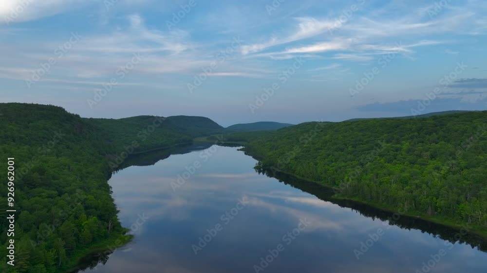 A breathtaking view of Lake of the Clouds at sunset during July, captured by drone footage in the Porcupine Mountains, Upper Peninsula, Michigan. The tranquil lake reflects the serene sky. A breathtaking view of Lake of the Clouds at sunset during July, captured by drone footage in the Porcupine Mountains, Upper Peninsula, Michigan. The tranquil lake reflects the serene sky.