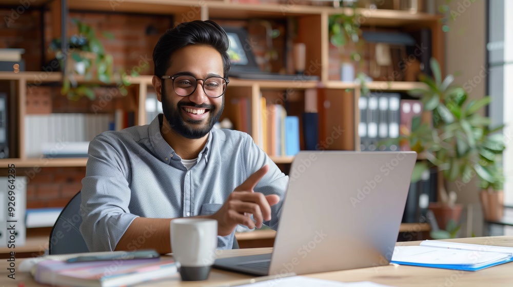Happy businessman sitting at his desk laughing while working on his laptop in the office Happy businessman sitting at his desk laughing while working on his laptop in the office