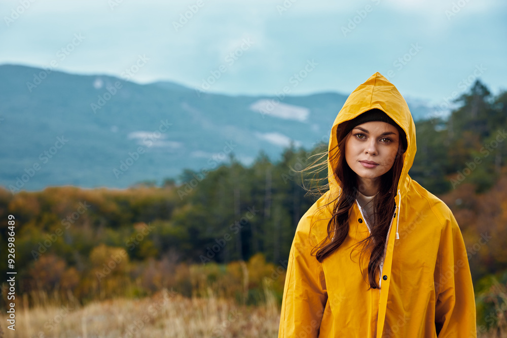 Serene Woman in Yellow Raincoat Standing in Field with Majestic Mountains in Background, Travel and Nature Concept Serene Woman in Yellow Raincoat Standing in Field with Majestic Mountains in Background, Travel and Nature Concept