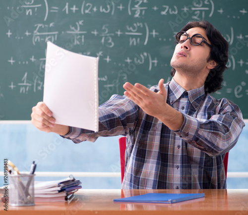 Young funny math teacher in front of chalkboard