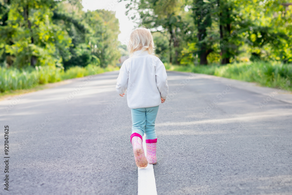 A Young Child Strolling Along a Roadway Surrounded by Vibrant, Lush Green Nature A Young Child Strolling Along a Roadway Surrounded by Vibrant, Lush Green Nature