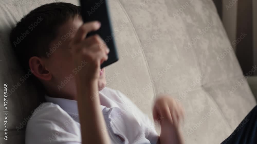 concept of joy of boy using phone, caucasian boy 10 years old looking at smartphone screen and surprisedly happy sitting on sofa at home concept of joy of boy using phone, caucasian boy 10 years old looking at smartphone screen and surprisedly happy sitting on sofa at home