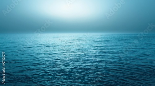 The image captures a serene and peaceful scene of a vast ocean, with calm blue waters rippling gently under a hazy sky.