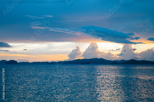 A view of the sea under a blue sky alternating with light yellow before the sun goes down. mountains and fjords Sea waves at the beach under a cloudy sky, Asia, Krabi, Thailand