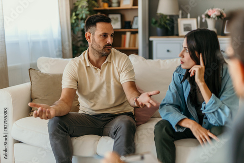 Man and woman sitting on couch and talking while psychologist listening to them