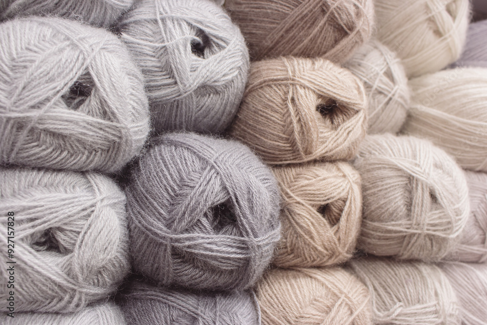 Grey and beige balls of yarn in storage. Warm wool yarn background. Knitting hobby. Row of grey and beige yarn. Handiwork store. Knit background. Handcraft concept. Knit pattern.