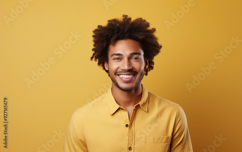 A man with a big smile on his face is wearing a yellow shirt. He is posing for a picture and he is happy