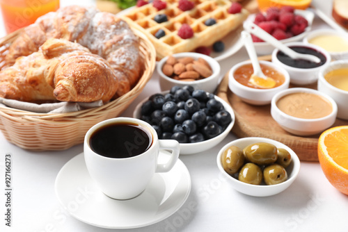 Cup of coffee and different meals served for breakfast on white table