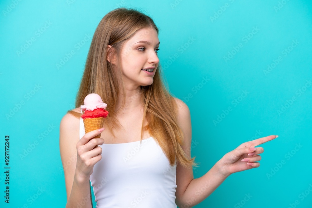 Teenager Russian girl with a cornet ice cream isolated on blue background pointing to the side to present a product Teenager Russian girl with a cornet ice cream isolated on blue background pointing to the side to present a product