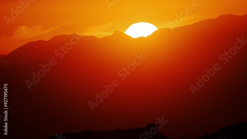 Establishing shot of the sun setting behind the mountain, captured with a handheld camera and slow pan. The gentle motion and warm tones create a peaceful, immersive experience of the golden hour.