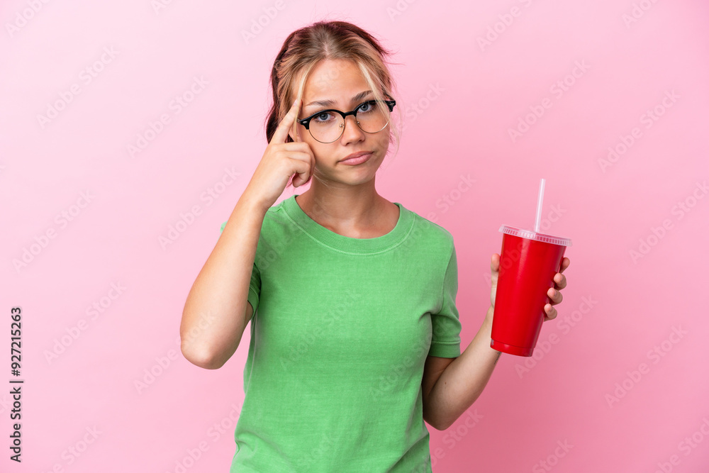 Young Russian woman holding a refreshment isolated on pink background thinking an idea Young Russian woman holding a refreshment isolated on pink background thinking an idea