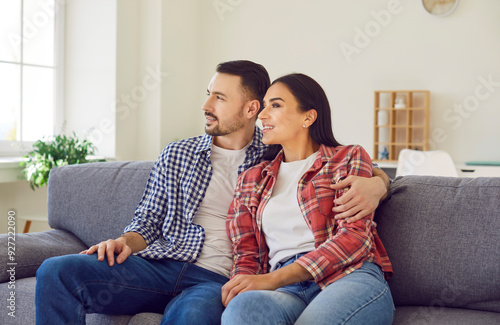 Young happy couple smiling couch sitting together close, man woman pair in hug. People acquiring new house, enjoy family life, moving into new residence, feel safe and comfortable