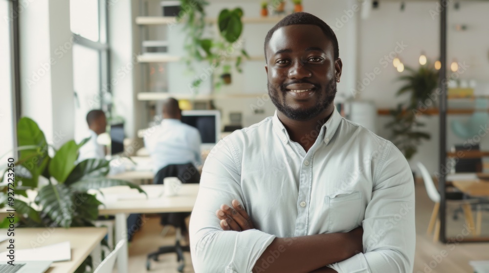 Obraz premium A confident man with a warm smile stands in a modern, plant-filled office, embodying professionalism and leadership.