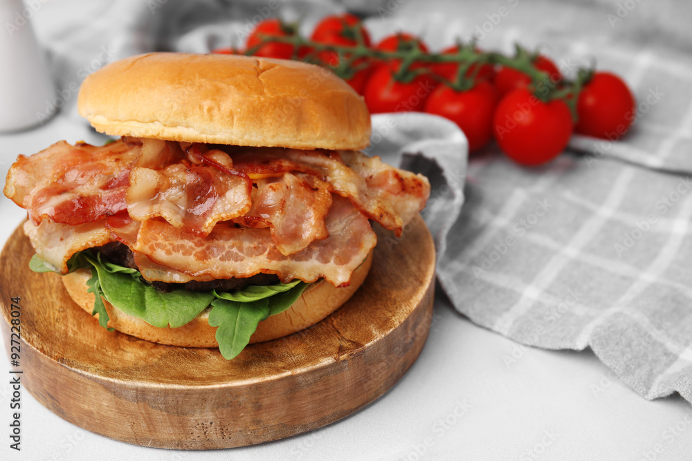 Delicious burger with bacon and greens on white table, closeup Delicious burger with bacon and greens on white table, closeup