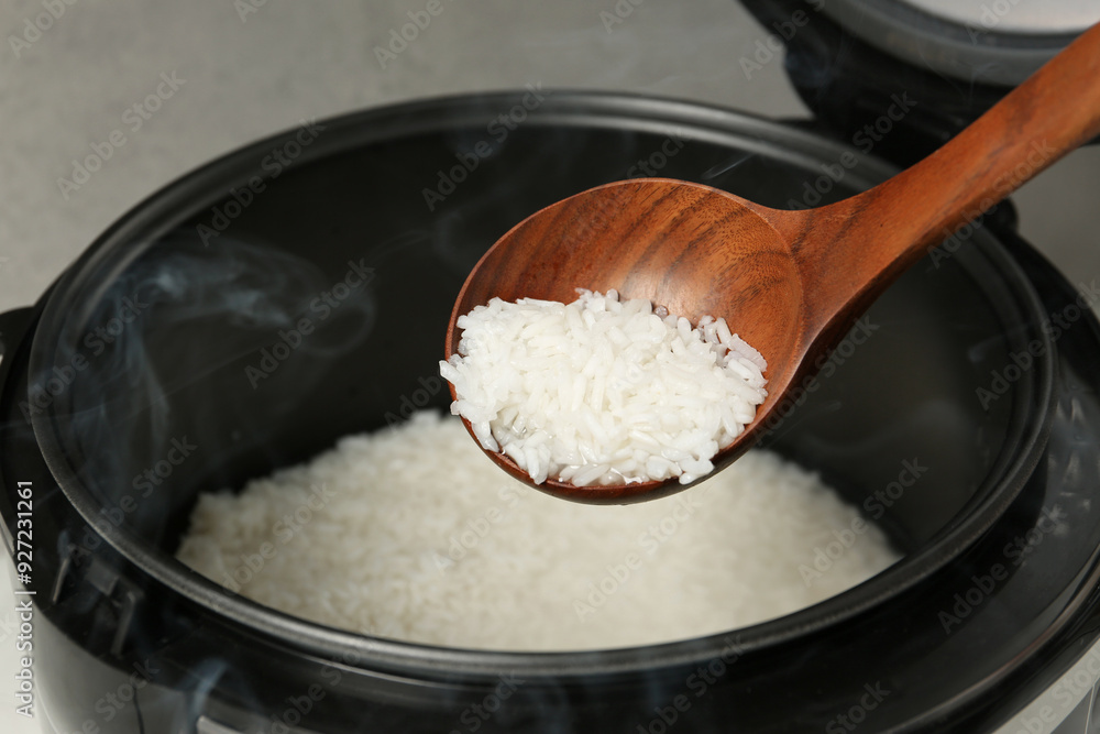 Taking boiled rice with wooden spoon on grey background, closeup Taking boiled rice with wooden spoon on grey background, closeup