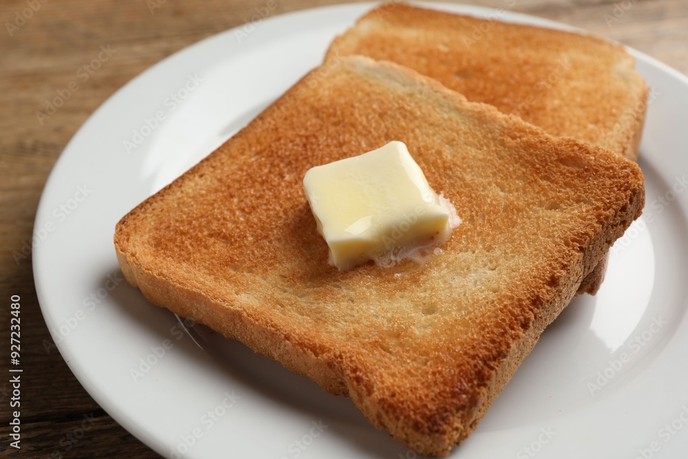 Delicious toasted bread slices with butter on table, closeup