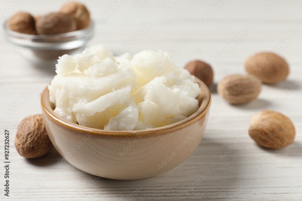 Shea butter in bowl and nuts on white wooden table, closeup Shea butter in bowl and nuts on white wooden table, closeup