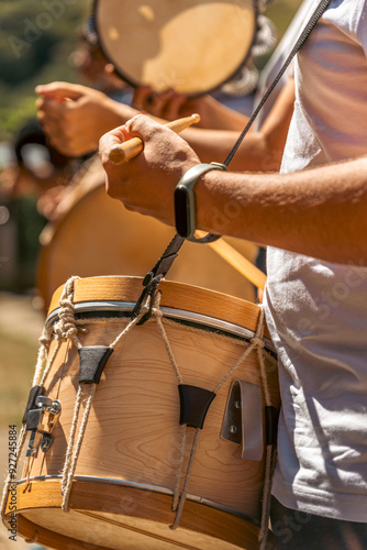 Detail of hands playing a typical Galician drum in a traditional folk music band on a street in a rural town in Galicia on a sunny day.