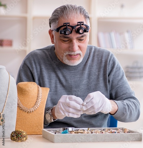 White bearded old jeweler at workshop photo