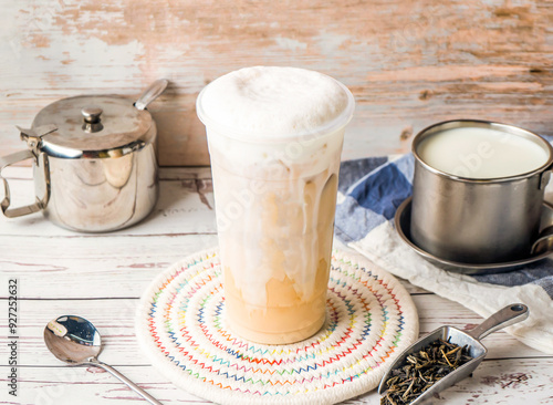 Iced Tieguanyin with Fresh Milk Tea or Tie guan yin with sugar pot and spoon served in disposable glass isolated on table side view of hong kong tea photo