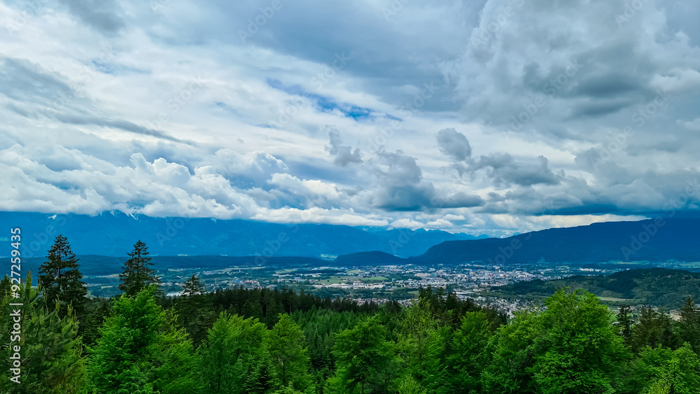 Panoramic aerial view of the city of Villach surrounded by majestic mountain ranges of Julian Alps and Karawanks, Carinthia, Austria, Europe. Idyllic forest walk near the Landskron Castle. Cityscape. Panoramic aerial view of the city of Villach surrounded by majestic mountain ranges of Julian Alps and Karawanks, Carinthia, Austria, Europe. Idyllic forest walk near the Landskron Castle. Cityscape.