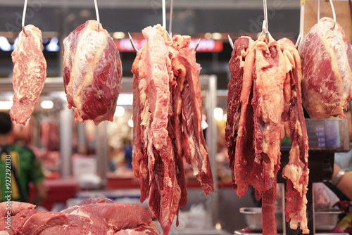 Various cuts of beef are hung on hooks. Different cuts of beef are displayed for customers to choose from.