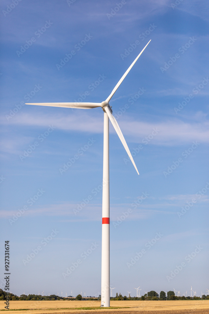 Ein Windrad auf einem Feld in der Natur mit blauem Himmel Ein Windrad auf einem Feld in der Natur mit blauem Himmel